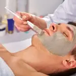 Mud facial mask of man in spa salon. Massage with clay full face in therapy room. | Aztec Secret Health & Beauty LTD